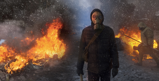 A person wearing a gas mask and standing in front of a fire