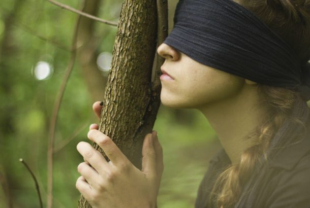 Woman blindfolded holding a tree