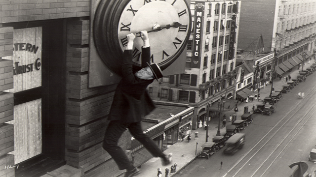 Harold Lloyd hanging by his fingertips from a clock in Safety Last!
