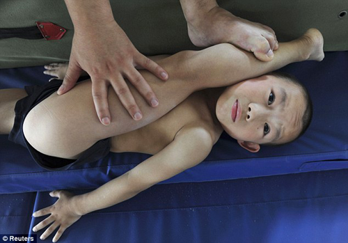 Young Chinese gymnast being stretched