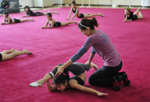 Young Chinese gymnast being stretched