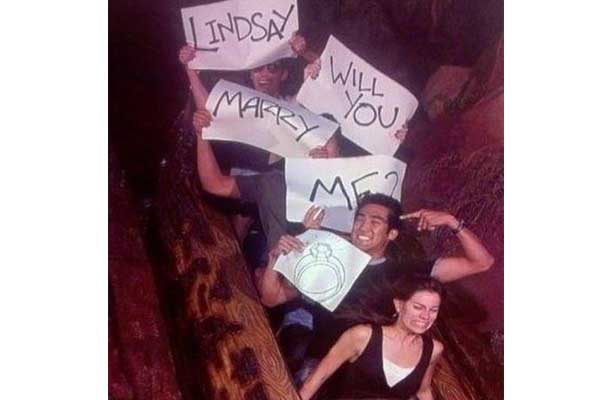 Man and friends with signs saying Lindsay will you marry me