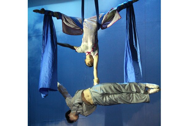 woman holding man hanging from silks
