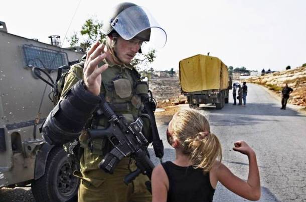 A young Palestinian girl launches a fist at a soldier in Nabi Saleh