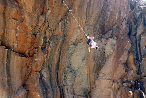 Man upside down midway down a cliffface