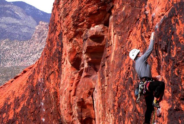 woman climbs up red rock mountain
