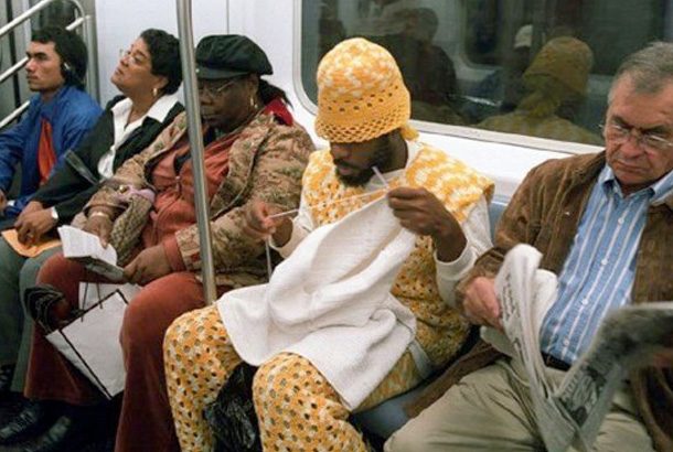 man in knitted outfit knitting