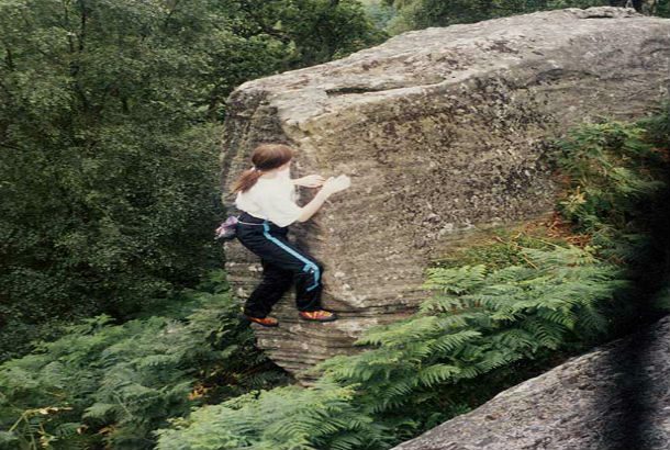 woman tip toes around boulder