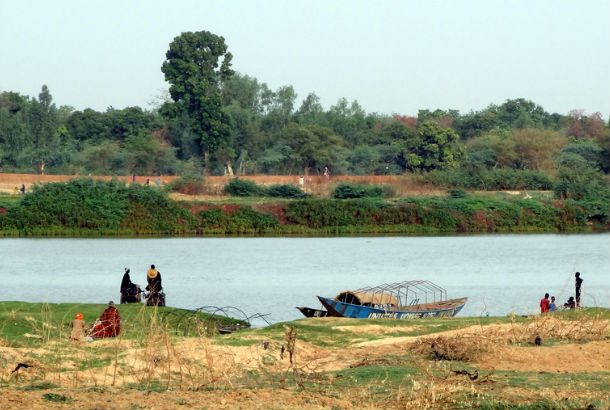 Niger river with boat and people in foreground and trees in background