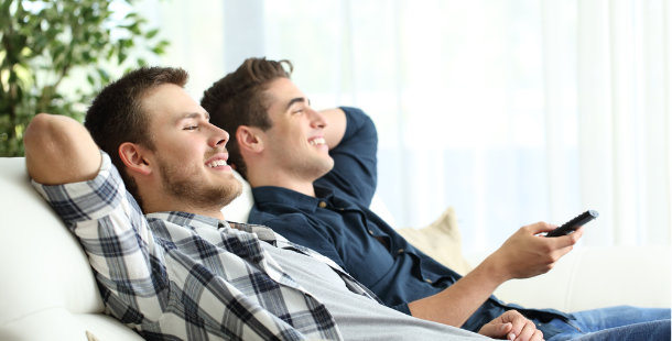 Guys on couch smiling and watching tv