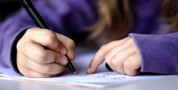 A close-up of a kids writing on a piece of paper