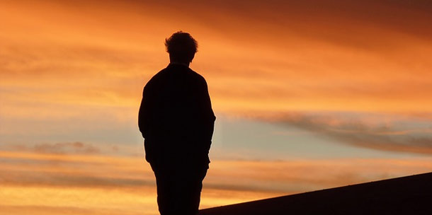 A silhouette of a person standing on a roof