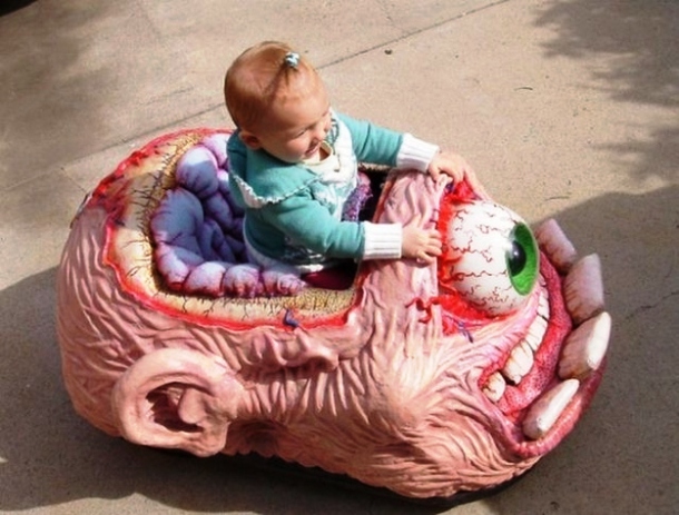 a baby sitting in a inappropriate toys head shaped object