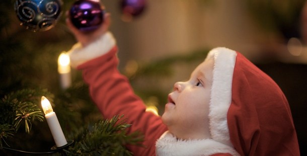 A child in santa garment holding a ornament, christmas facts