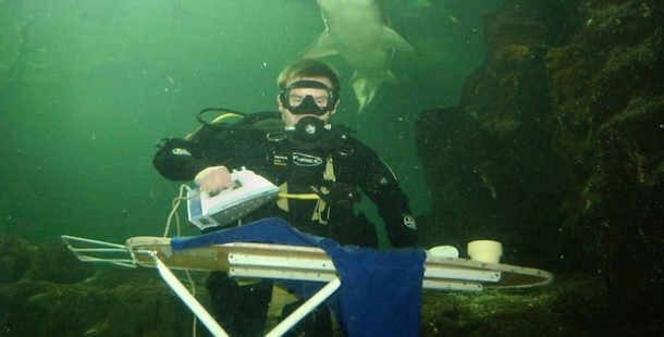 A person ironing clothes under water