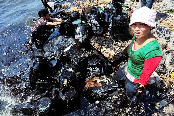 Woman helps to clean up oil at an oil spill site near Dalian Port, Liaoning Province.