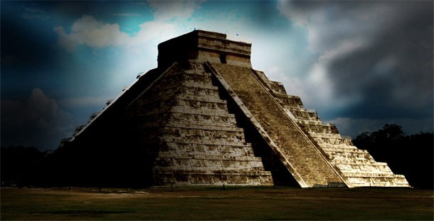 A pyramid with steps leading to the top with chichen itza in the background