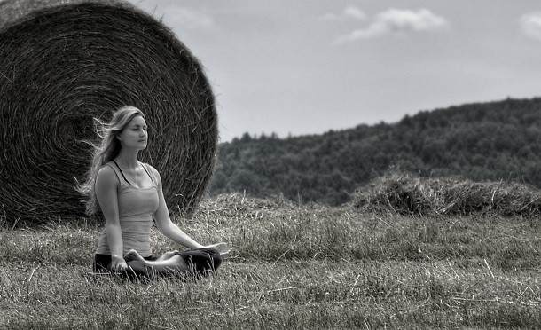 woman meditating next to hay bale
