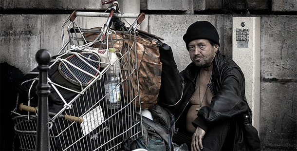 A homeless person sitting next to a shopping cart