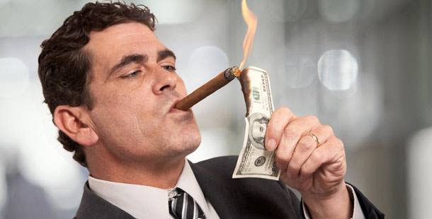 A person lighting a cigar with a money bill