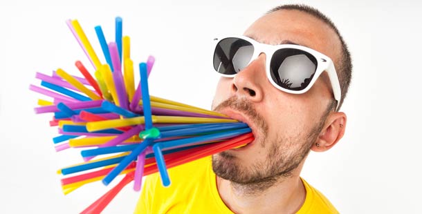 A guiness world record of a person with sunglasses and a bunch of colorful straws in his mouth