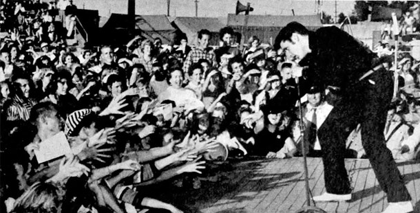 A person singing into a microphone with a crowd of people