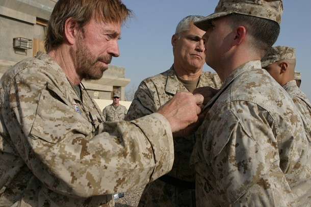 Actor Chuck Norris places corporal chevrons on U.S. Marine Corps Cpl. John Wright
