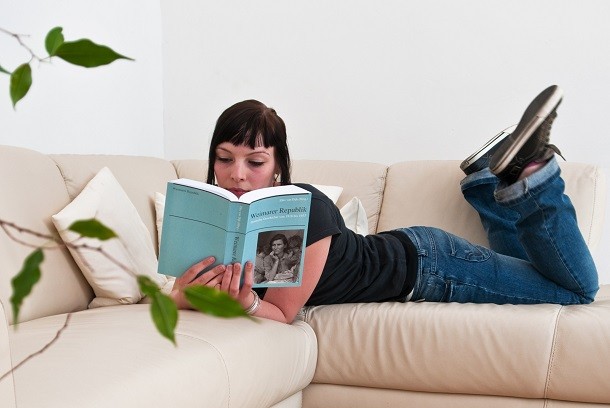 girl reading book on sofa