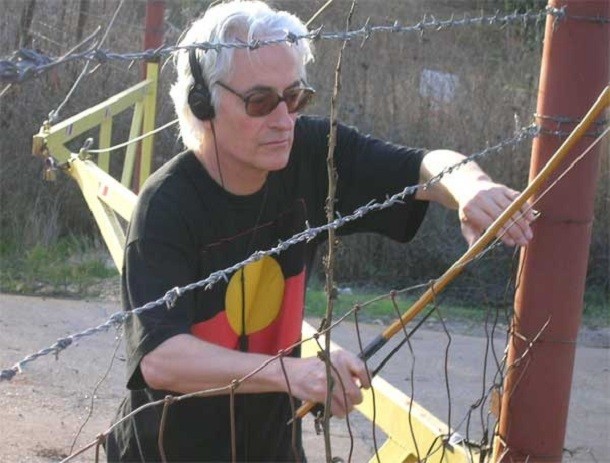 jon rose bowing a kibbutz fence to the south of the golan heights, photo victor levin