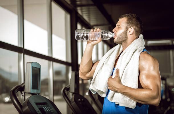 Guy drinking water while at the gym