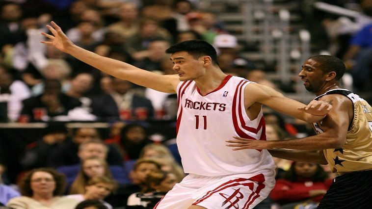 A basketball player in a white jersey with his arms out