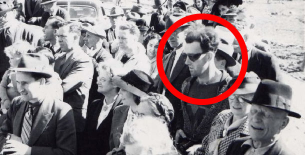 A person in sunglasses and hat in a crowd