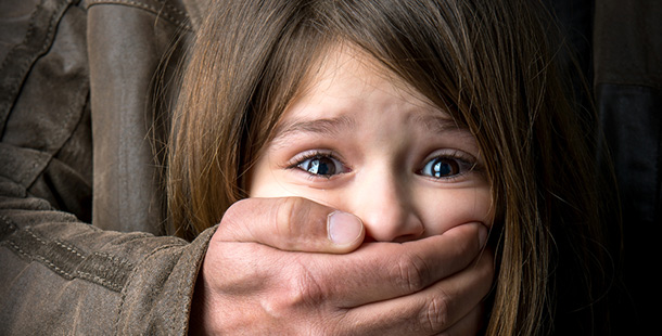 A close-up of a child covering her mouth