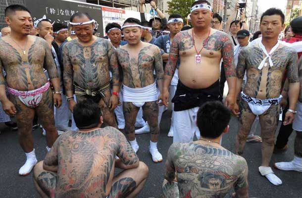Seven Yakuza Men displaying tattoos at a festival