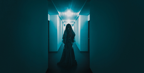 A dark corridor with a dark figure standing in the middle