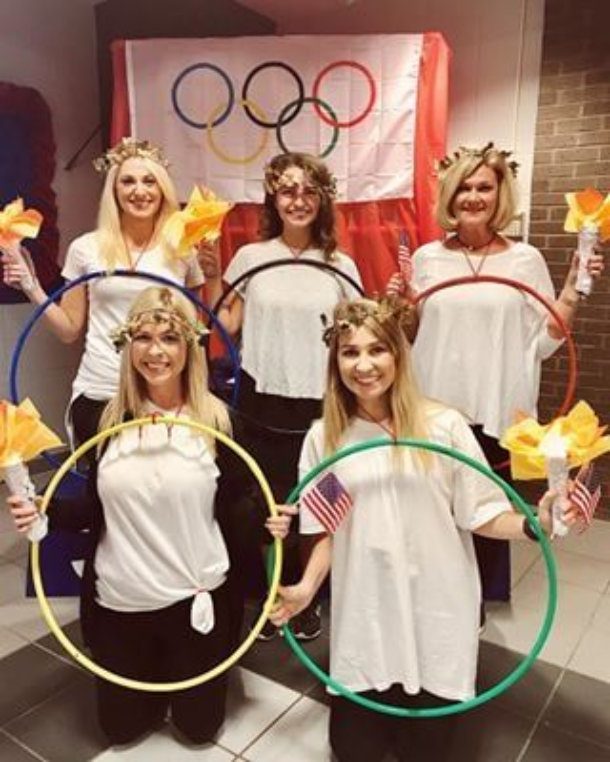 women wearing white shirts holding colored hulahoops to represent the olympic rings