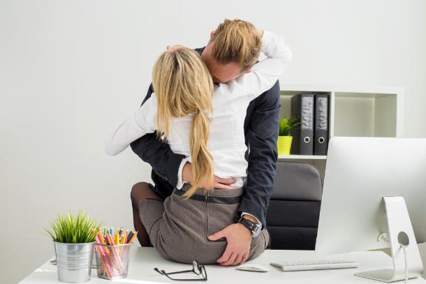 man and woman kissing on desk