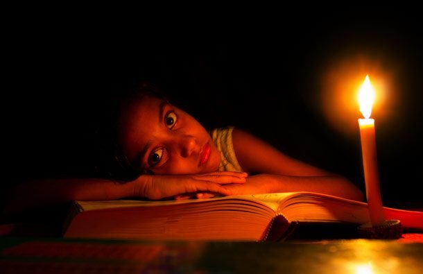 Little girl trying to read in the dark with a candle