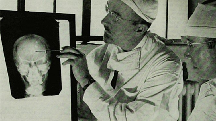 A person in a white coat and glasses