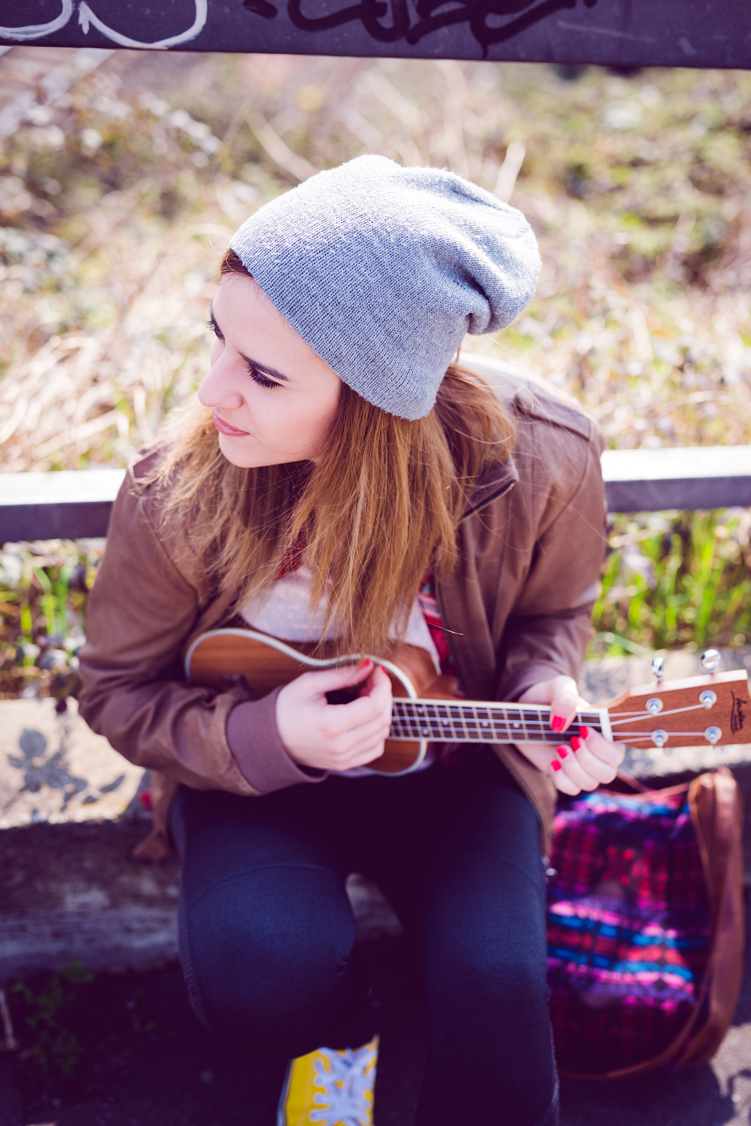 young beautiful blonde hipster woman in the city playing ukulele