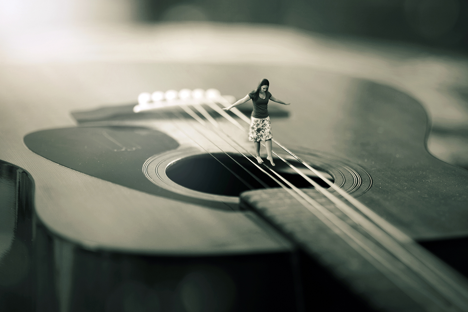 A surreal image of a woman balancing on strings of a guitar