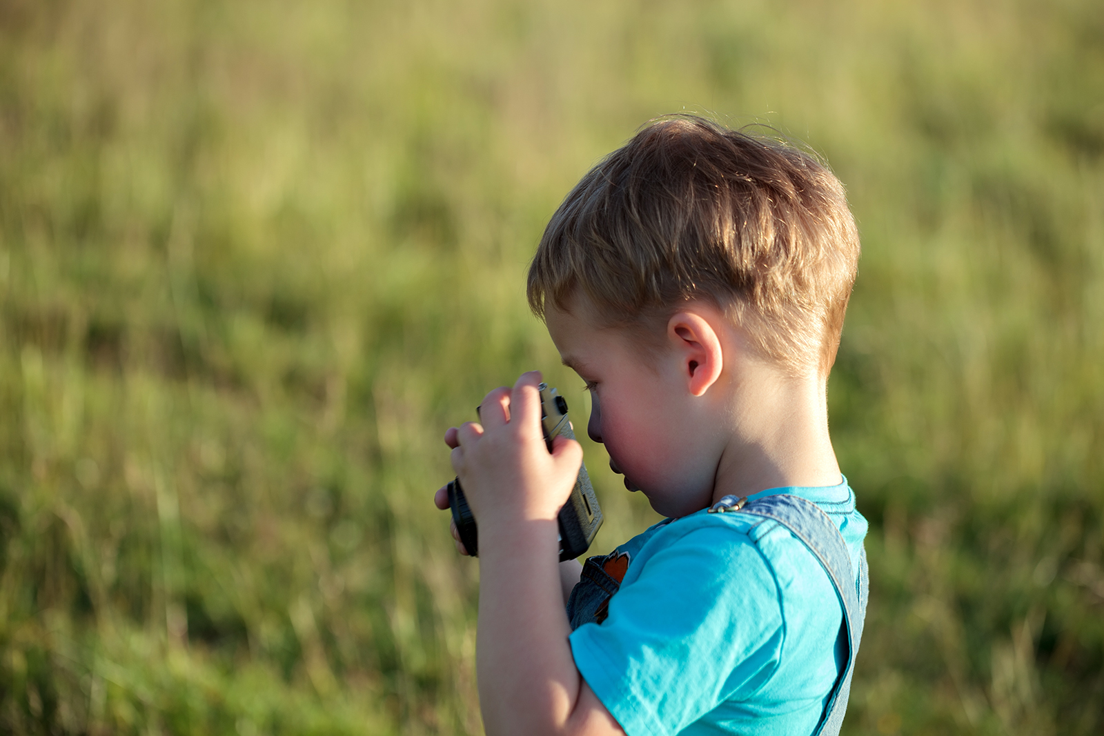 Little boy trying to make photos with camera outdoor